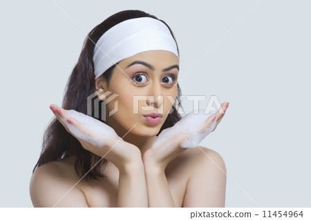 Portrait of beautiful woman with soap sud pouting against gray background 11454964