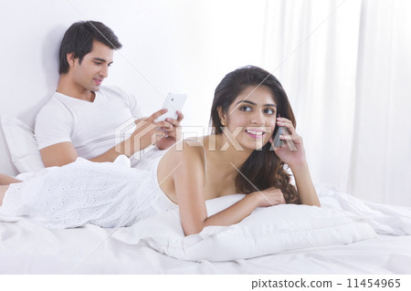 Young woman on call with man using digital tablet in bedroom 11454965
