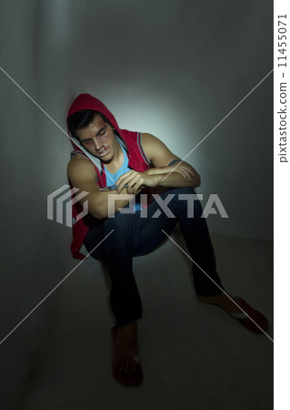 Full length of unconscious drug addict holding syringe against wall 11455071