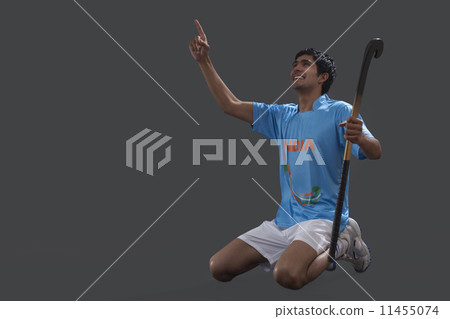 Happy young hockey player with stick celebrating success over gray background 11455074