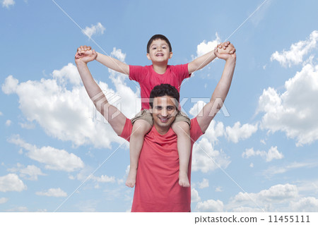 Portrait of happy father carrying son on shoulders against cloudy sky 11455111