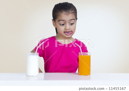 Confused girl choosing between juice and milk against colored background 11455167