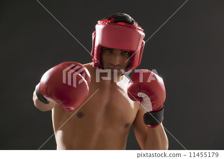 Portrait of male boxer wearing gloves and head protector isolated over black background 11455179
