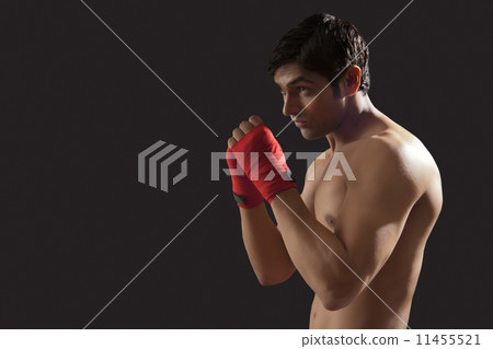 Side view of young male boxer practicing isolated over black background Side view of young male boxer practicing isolated over black background 11455521