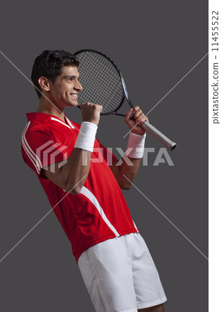 Happy young tennis player celebrating success over black background Happy young tennis player celebrating success over black background 11455522
