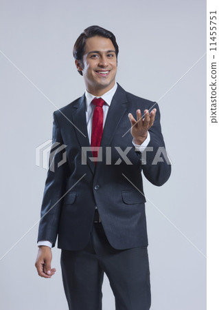 Portrait of happy businessman gesturing against gray background Portrait of happy businessman gesturing against gray background 11455751