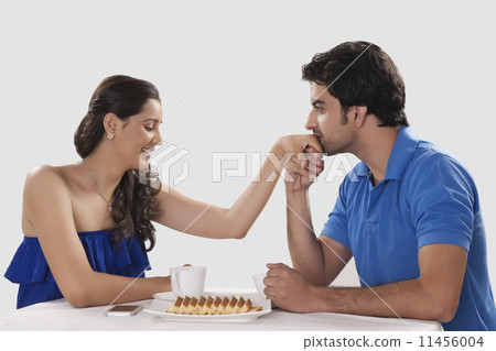Loving man kissing woman on hand while having coffee against white background Loving man kissing woman on hand while having coffee against white background 11456004