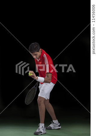 Male tennis player preparing to serve over black background 11456006