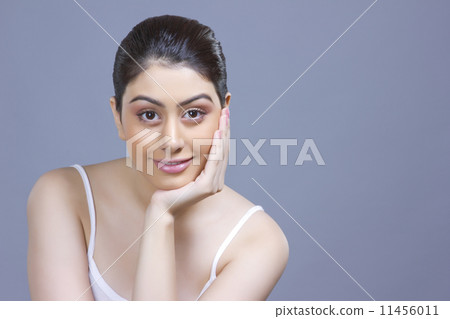 Portrait of beautiful woman with hand on chin over blue background 11456011