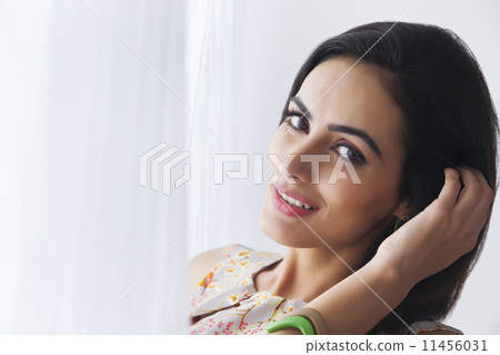 Close-up portrait of beautiful young woman by curtains 11456031