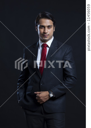 Portrait of confident businessman with hand in pocket over black background Portrait of confident businessman with hand in pocket over black background 11456059