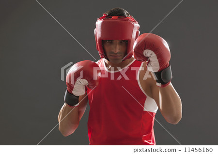 Portrait of male boxer wearing head protector and gloves isolated over gray background 11456160