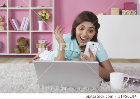 Surprised young woman reading text message on mobile phone at home Surprised young woman reading text message on mobile phone at home 11456184