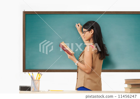 Female college student writing on blackboard 11456247