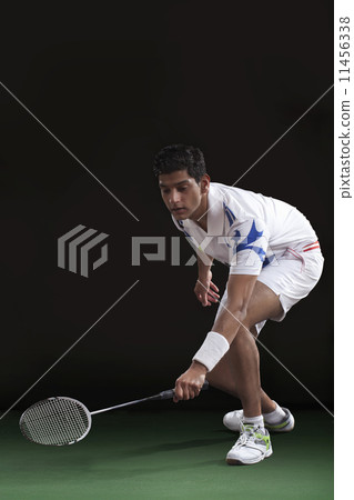 Young man in sportswear playing badminton over black background Young man in sportswear playing badminton over black background 11456338