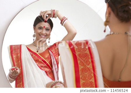Portrait of Bengali woman putting sindoor on her forehead Portrait of Bengali woman putting sindoor on her forehead 11456524