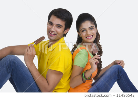 Portrait of beautiful young couple eating ice-cream bars over white background Portrait of beautiful young couple eating ice-cream bars over white background 11456542