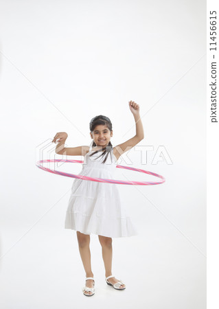 Portrait of a little girl twirling hoop around waist Portrait of a little girl twirling hoop around waist 11456615