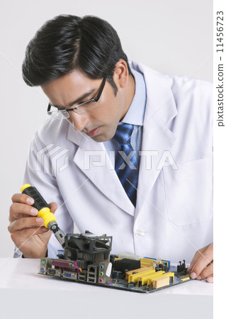 Young technician repairing machine part at table over gray background 11456723