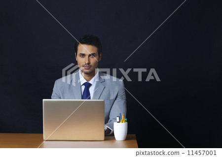 Portrait of handsome young businessman using laptop in office Portrait of handsome young businessman using laptop in office 11457001