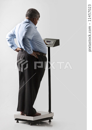 Obese man checking his weight 11457023