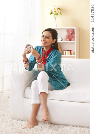 Full length portrait of happy young woman using mobile phone on sofa Full length portrait of happy young woman using mobile phone on sofa 11457086