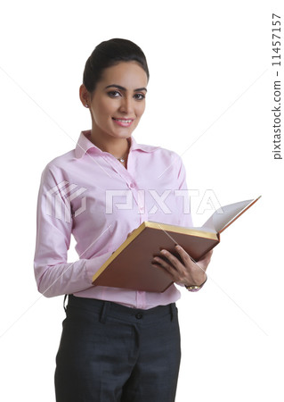 Portrait of confident young businesswoman holding diary over white background Portrait of confident young businesswoman holding diary over white background 11457157
