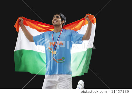 Young hockey player looking up as he holds Indian flag with pride against black background Young hockey player looking up as he holds Indian flag with pride against black background 11457189