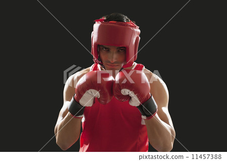 Portrait of male boxer wearing head protector and gloves isolated over black background 11457388