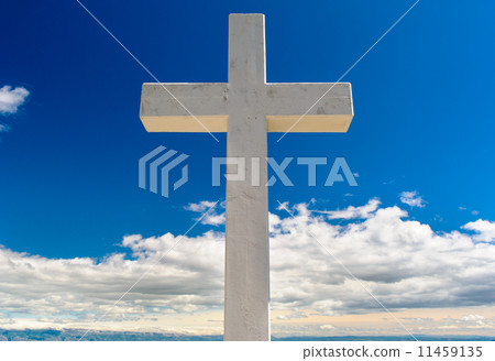White cross against blue sky and fluffy clouds 11459135
