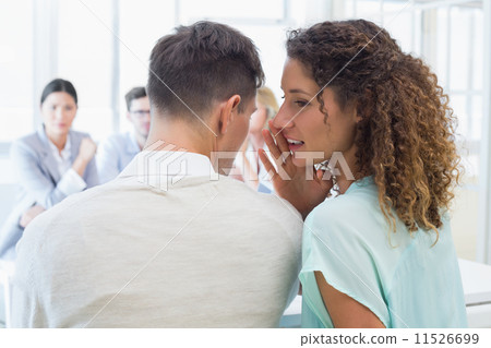 Casual businesswoman telling a secret to colleague 11526699