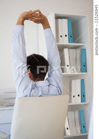 Casual businessman stretching in swivel chair Casual businessman stretching in swivel chair 11526945