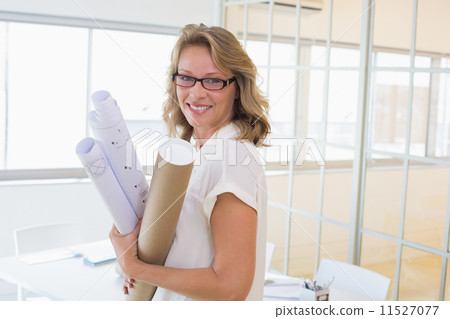 Casual architect smiling at camera holding blueprints 11527077