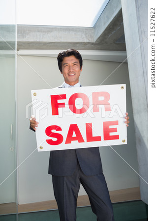 Confident estate agent standing at front door showing for sale s 11527622