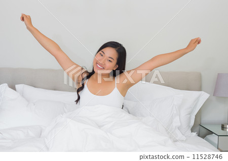 Smiling woman stretching in bed in the morning 11528746