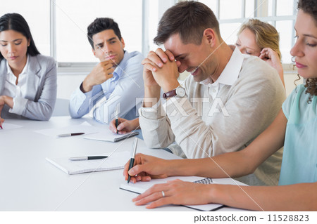 Casual businessman trying not to laugh during meeting 11528823