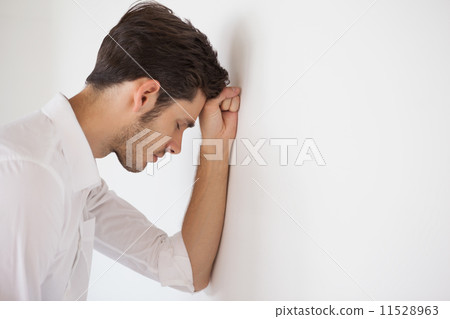 Casual businessman leaning against the wall 11528963
