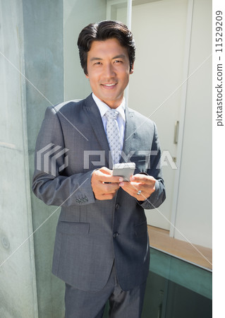 Confident estate agent standing at front door texting Confident estate agent standing at front door texting 11529209