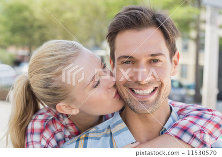 Young hip woman giving boyfriend kiss on the cheek 11530570