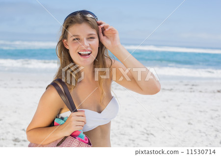 Beautiful smiling blonde on the beach holding bag 11530714