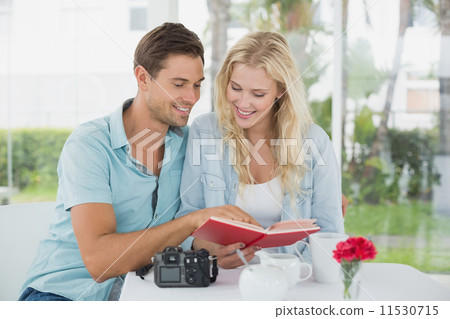 Cute hipster couple reading book together at table 11530715