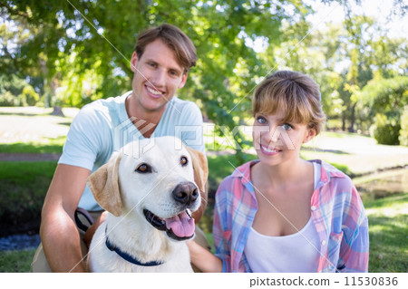 Cute couple with their labrador dog in the park Cute couple with their labrador dog in the park 11530836