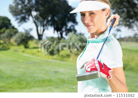 Female golfer standing holding her club smiling at camera Female golfer standing holding her club smiling at camera 11531082