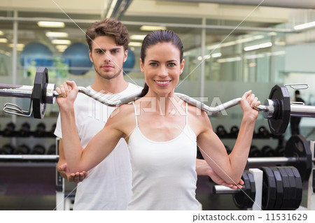 Fit smiling woman lifting barbell with her trainer Fit smiling woman lifting barbell with her trainer 11531629