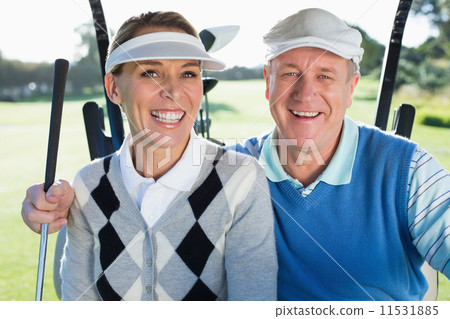 Happy golfing couple sitting in golf buggy smiling at camera Happy golfing couple sitting in golf buggy smiling at camera 11531885