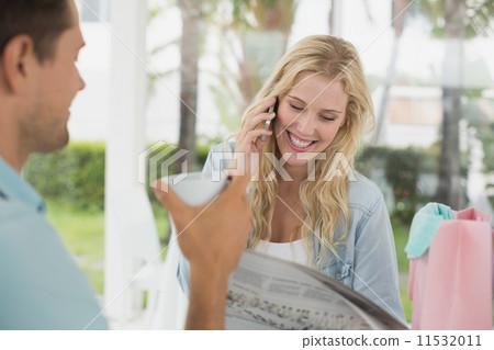 Pretty blonde talking on phone while having coffee with boyfrien 11532011