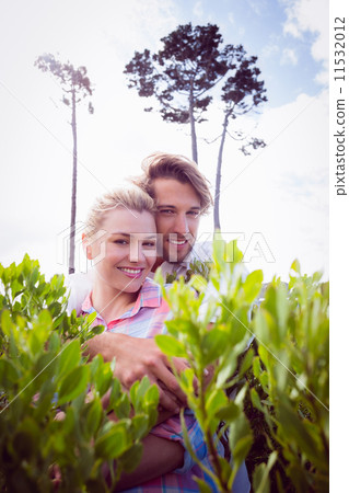Smiling couple embracing outside among the bushes 11532012