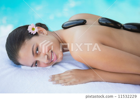 Relaxed brunette lying on towel having a hot stone massage 11532229