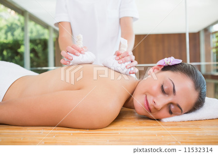Smiling woman getting a back massage with herbal compresses 11532314
