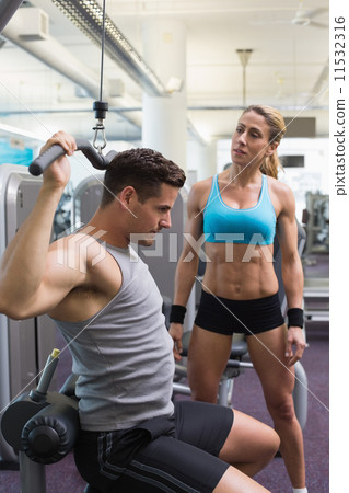 Bodybuilder using weight machine for arms with encouraging train 11532316
